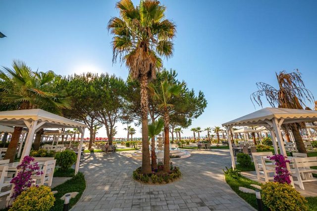 A tall palm at the centre of the promenade between two white gazebos